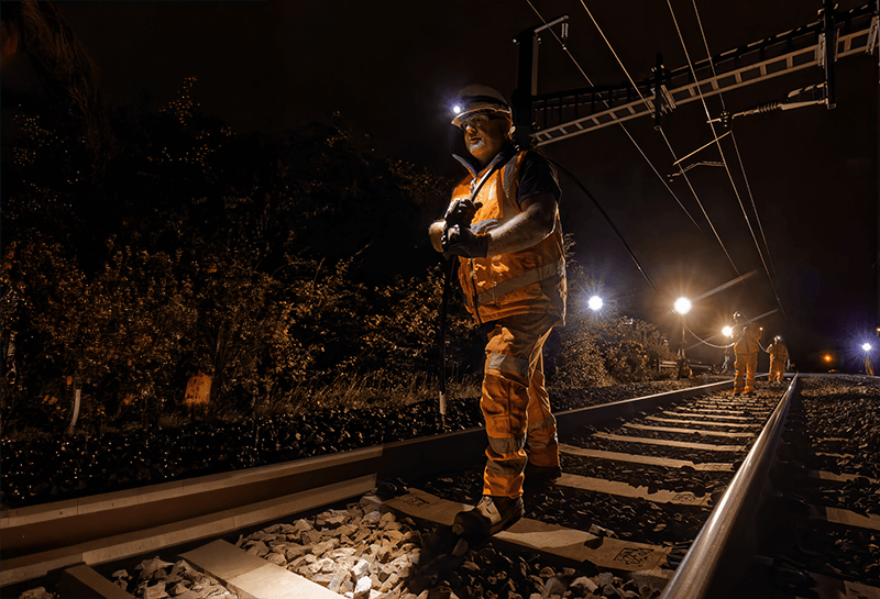 Engineers installing fibre cable along a railway line at night as part of Project Reach.